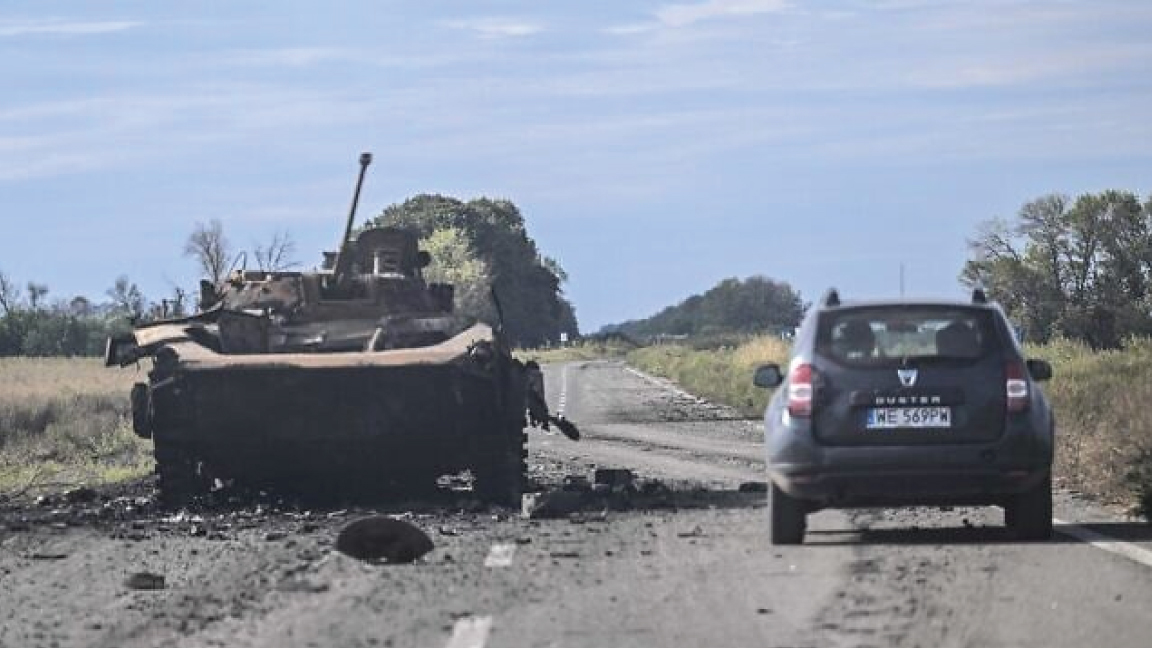 سيارة تمر أمام عربة مدرعة روسية مدمرة في بالاكليا ، منطقة خاركيف ، في 10 سبتمبر 2022 ، وسط الغزو الروسي لأوكرانيا