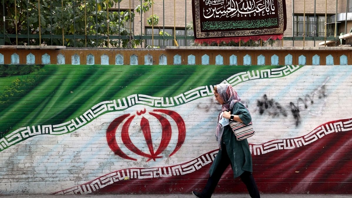 امرأة إيرانية تمشي أمام لوحة جدارية في العاصمة طهران