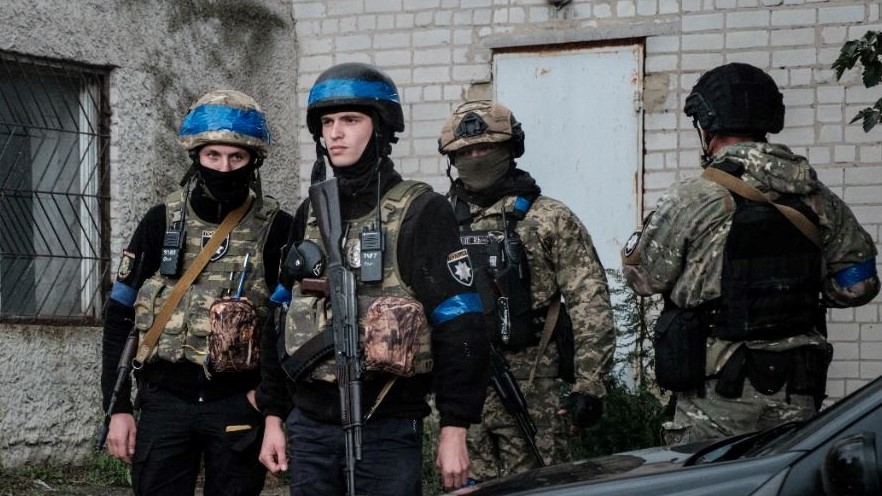 عناصر من الشرطة يحتمون من الأمطار في بلدة كوبيانسك على خط المواجهة في منطقة خاركيف في 24 سبتمبر 2022