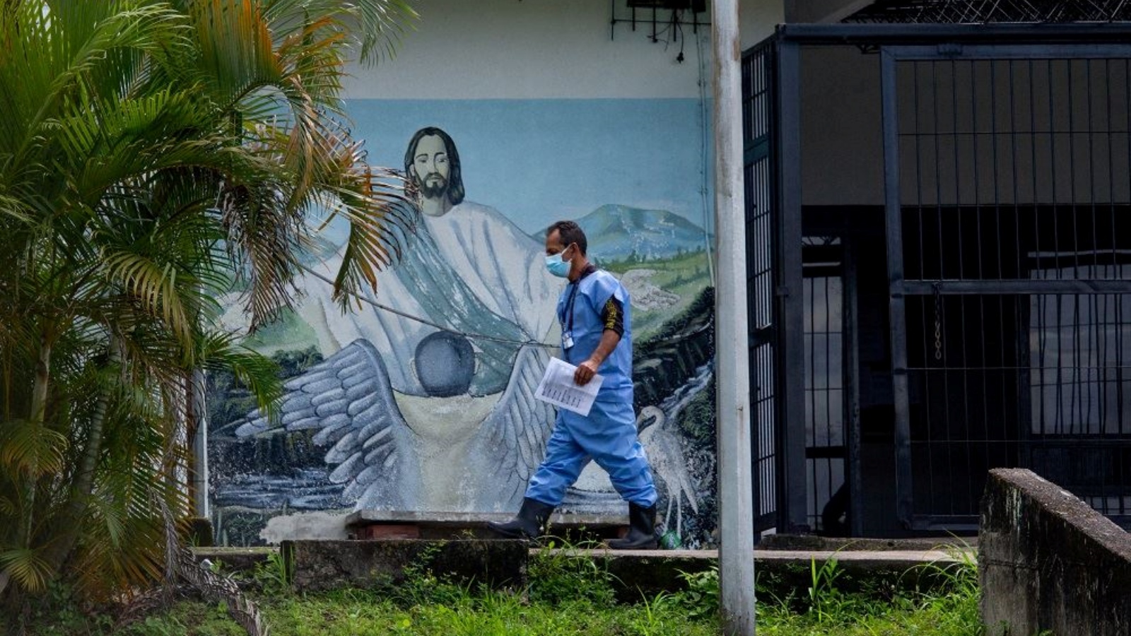 عضو من فيلق التحقيقات الجنائية والجنائية (CICP) يمشي أمام لوحة جدارية ليسوع المسيح في مشرحة سان كريستوبال في ولاية تاتشيرا