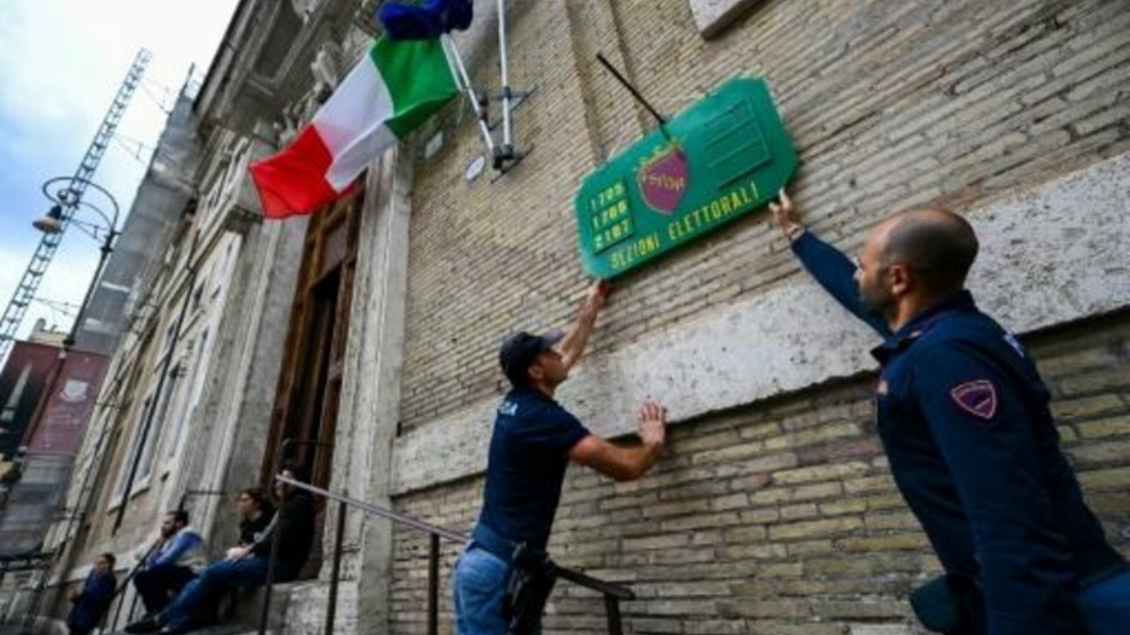 شرطيون يثبتون لافتة تشير إلى مركز اقتراع في روما في 24 سبتمبر 2022 عشية الانتخابات التشريعية الإيطالية