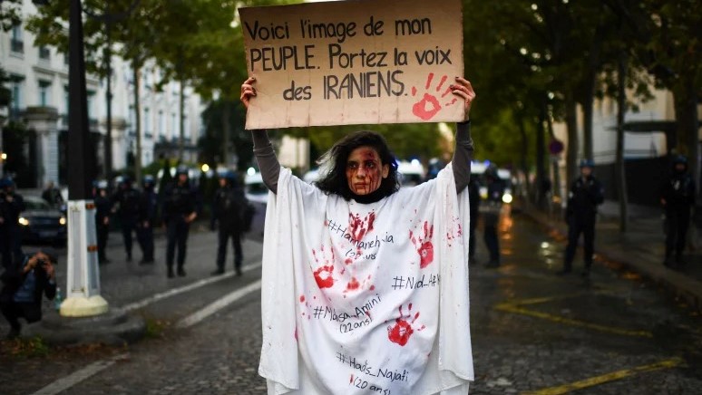 متظاهر يحمل لافتة كتب عليها 'هذه صورة شعبي. حمل صوت الإيرانيين ”وهي تقف أمام شرطة مكافحة الشغب خلال مظاهرة لدعم المتظاهرين الإيرانيين في باريس ، 25 سبتمبر 2022