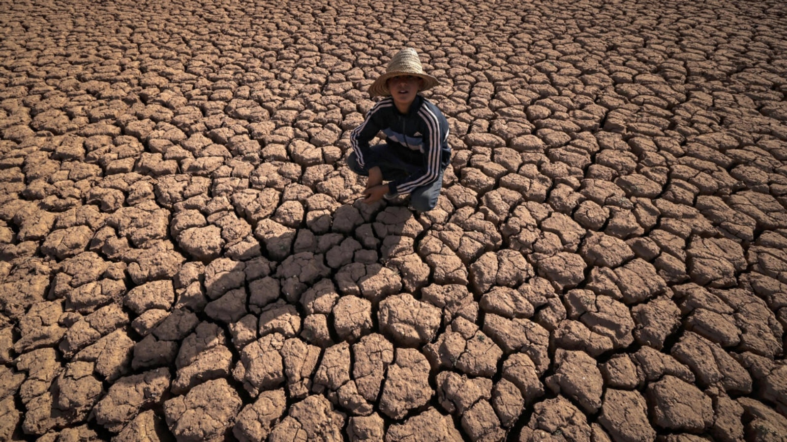 طفل يجلس على أرض مشققة بسبب الجفاف قرب سد المسيرة على بعد 140 كيلومتراً من الدار البيضاء في الثامن من أغسطس 2022 
