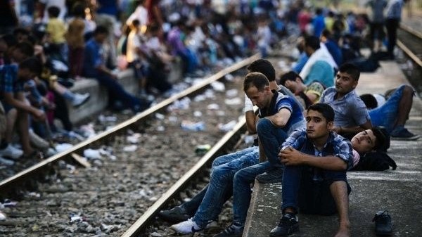 مهاجرون ينتظرون قطارا متجها إلى صربيا في محطة غيفغليا للسكك الحديدية، على الحدود المقدونية اليونانية