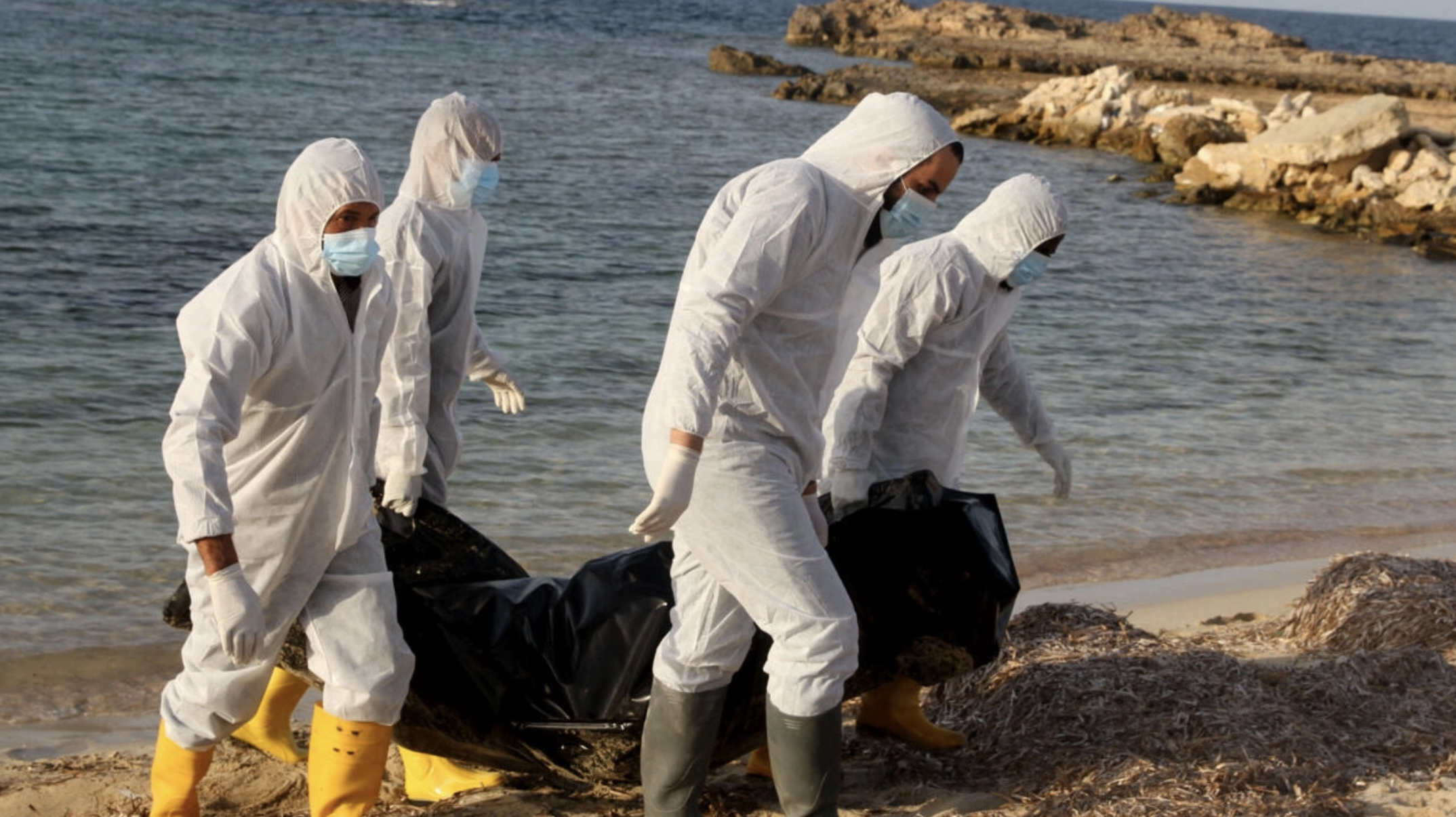 عاملين صحيين ليبيين ينتشلون جثث مهاجرين غرقى بعد غرق قارب قبالة شاطئ في صبراتة على بعد نحو 120 كيلومترًا غرب العاصمة الليبية طرابلس في 25 تشرين الثاني/نوفمبر 2021