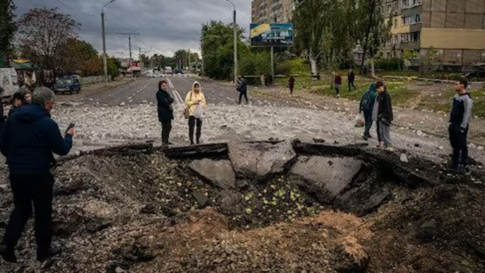 أشخاص حول حفرة خلفها القصف الروسي على أوكرانيا صباح الإثنين 11 أكتوبر 2022