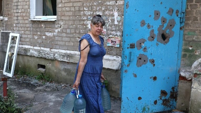 امرأة تحمل زجاجات مياه في بلدة أفدييفكا بمنطقة دونيتسك والتي تعرضت السوق فيها لقصف روسي اليوم 12 أكتوبر 2022