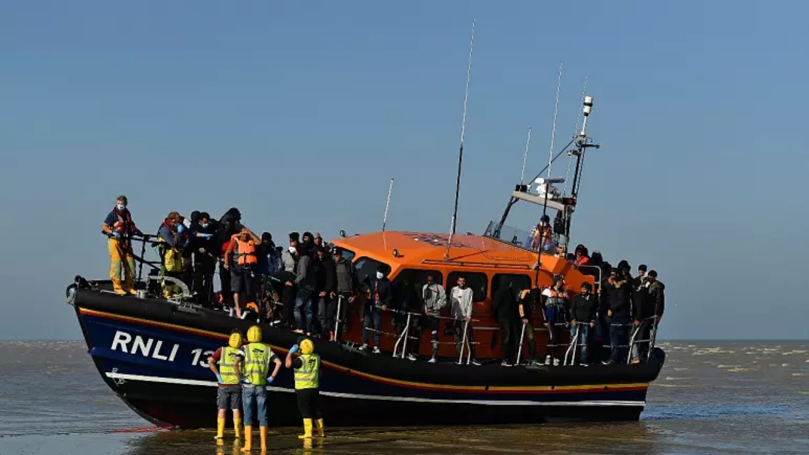 مهاجرون يقفون على متن قارب نجاة RNLI (المؤسسة الملكية الوطنية لقوارب النجاة) بعد أن يتم إنقاذهم عبر القناة الإنكليزية في Dungeness، إنكلترا، 7 سبتمبر 2021