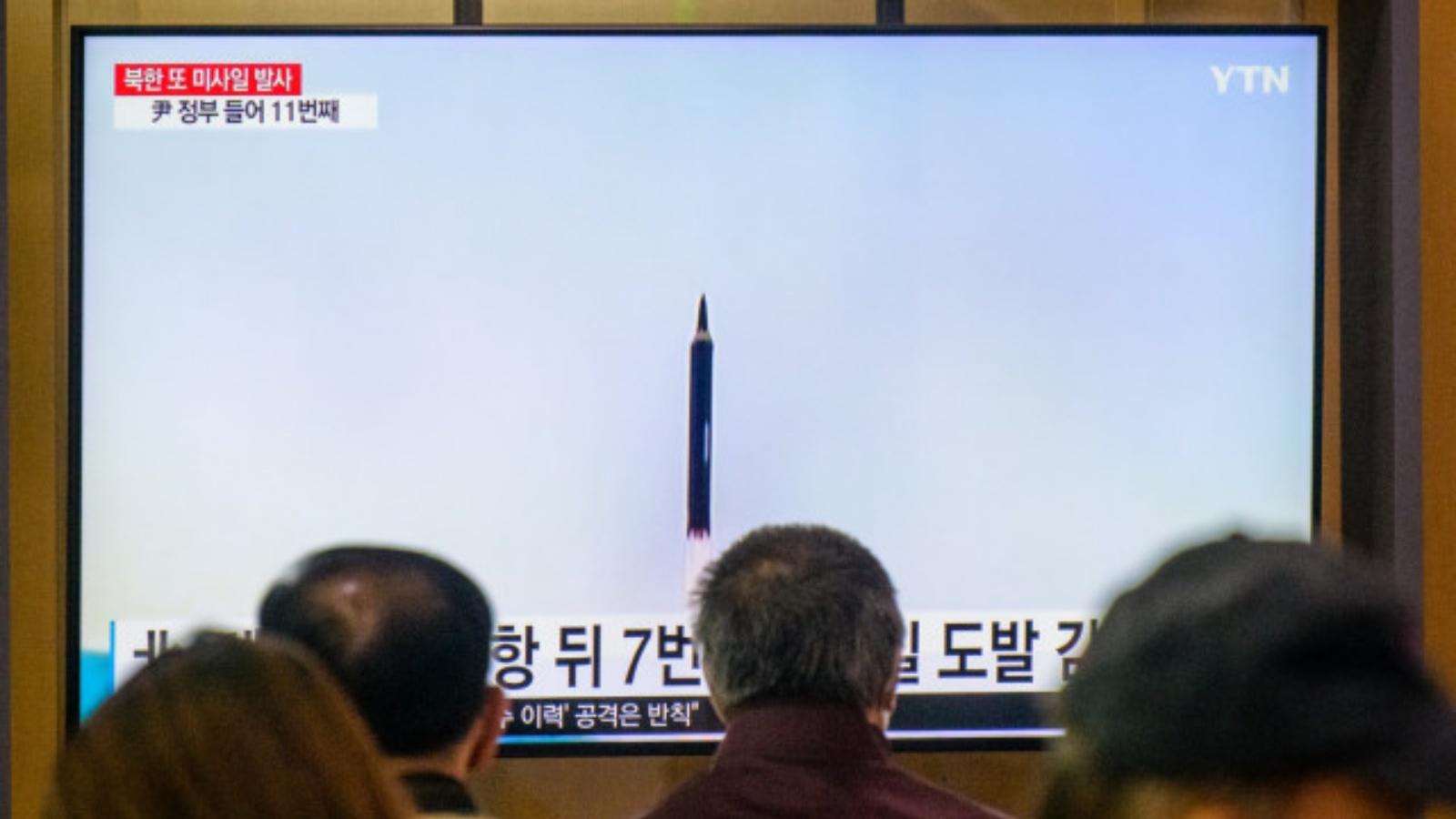 أشخاص يجلسون بالقرب من شاشة تلفزيون تُظهر بثًا إخباريًا مع ملف لقطات لتجربة صاروخ كوري شمالي، في محطة سكة حديد في سيول في 9 أكتوبر 2022
