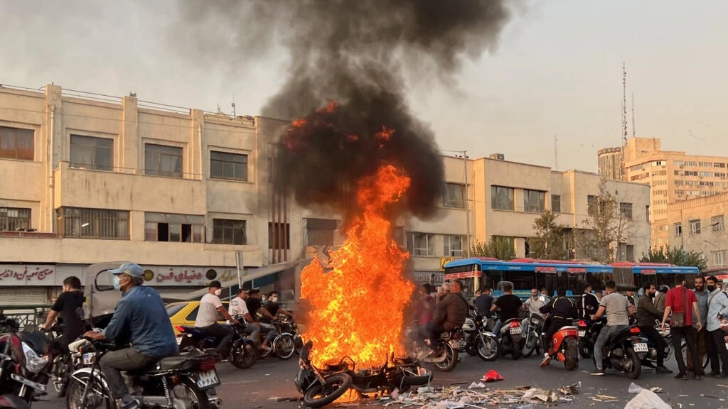صورة حصلت عليها فرانس برس من خارج إيران تظهر تجمع عدد من الأشخاص ودراجة نارية تحترق في العاصمة طهران في 8 تشرين الأول/أكتوبر 2022