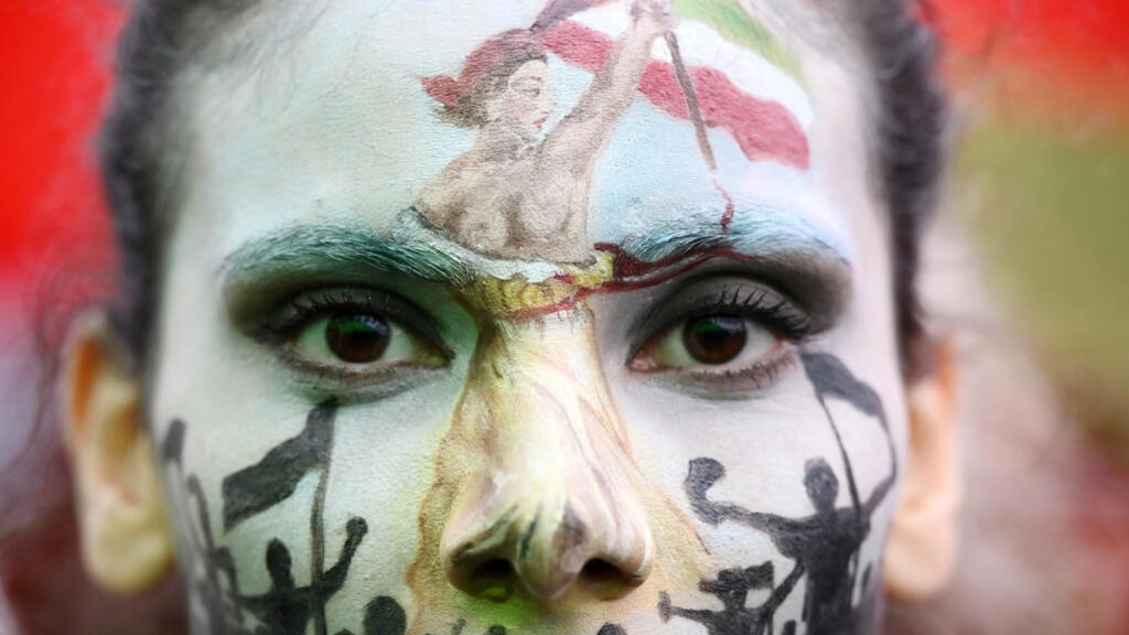 امرأة ترتدي طلاء وجه يصور 'ماريان' الفرنسية الشهيرة تقود انتفاضة تظهر في باريس ضد حملة القمع الدموية التي تشنها إيران على الاحتجاجات التي تقودها النساء ضد قواعد اللباس الصارمة في البلاد