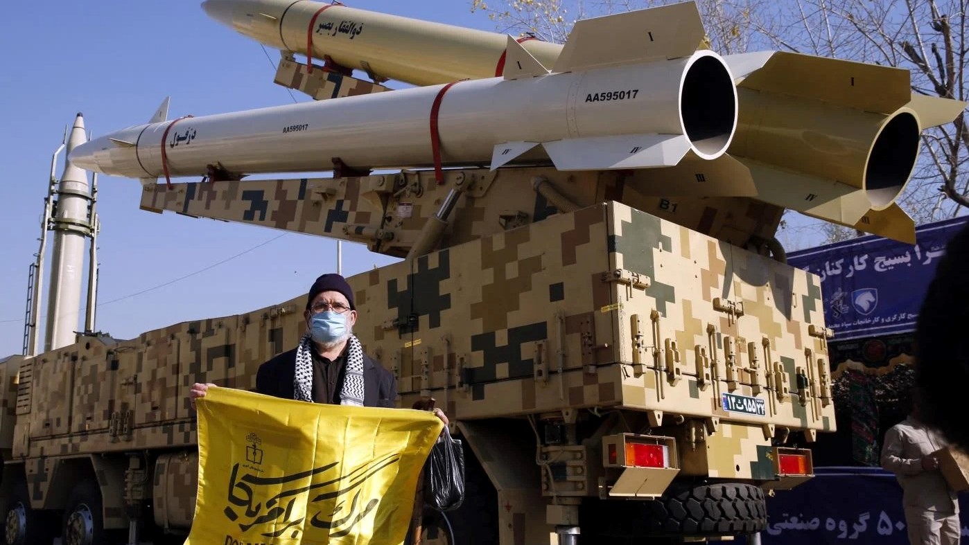 إيراني يحمل لافتة معادية للولايات المتحدة إلى جانب زوالجار بصير وصواريخ دزفول معروضة في مسجد الموصل بطهران في الذكرى الثانية لهجوم صاروخي إيراني على قاعدة عسكرية أميركية في العراق، في 7 يناير 2022