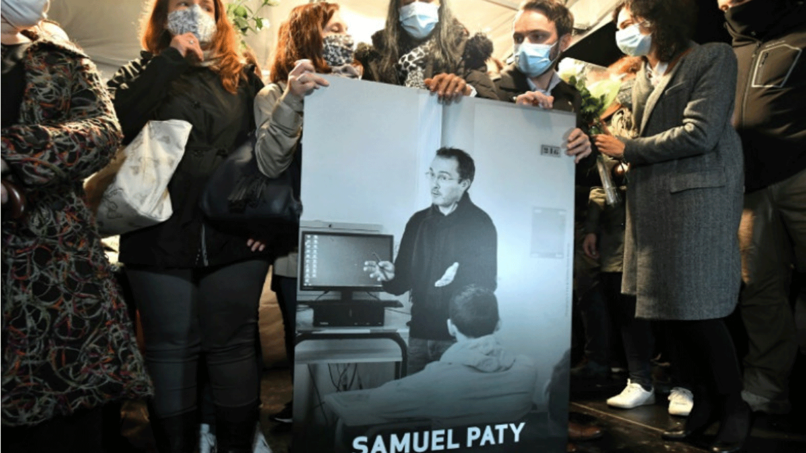 الأقارب والزملاء يحملون صورة صموئيل باتي في مسيرة صامتة في كونفلانس سانت أونورين حيث كان يعمل مدرسًا للتاريخ قبل مقتله.