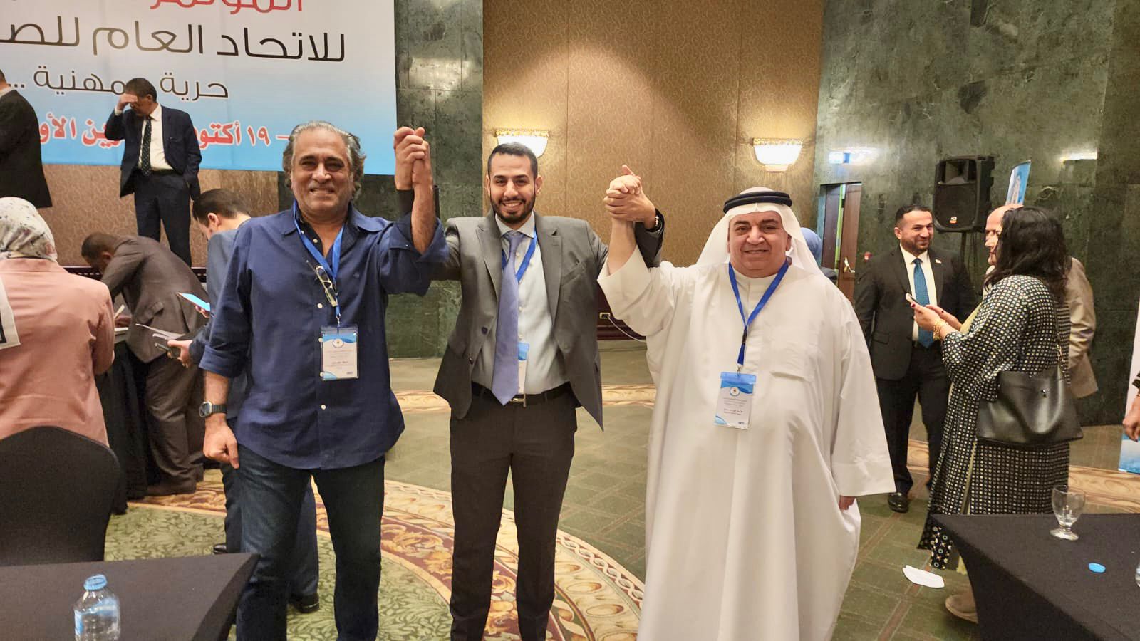 راشد نبيل الحمر يتوسط عضوين في الوفد البحريني عقب انتخابه امينا عاما مساعدا لاتحاد الصحافيين العرب