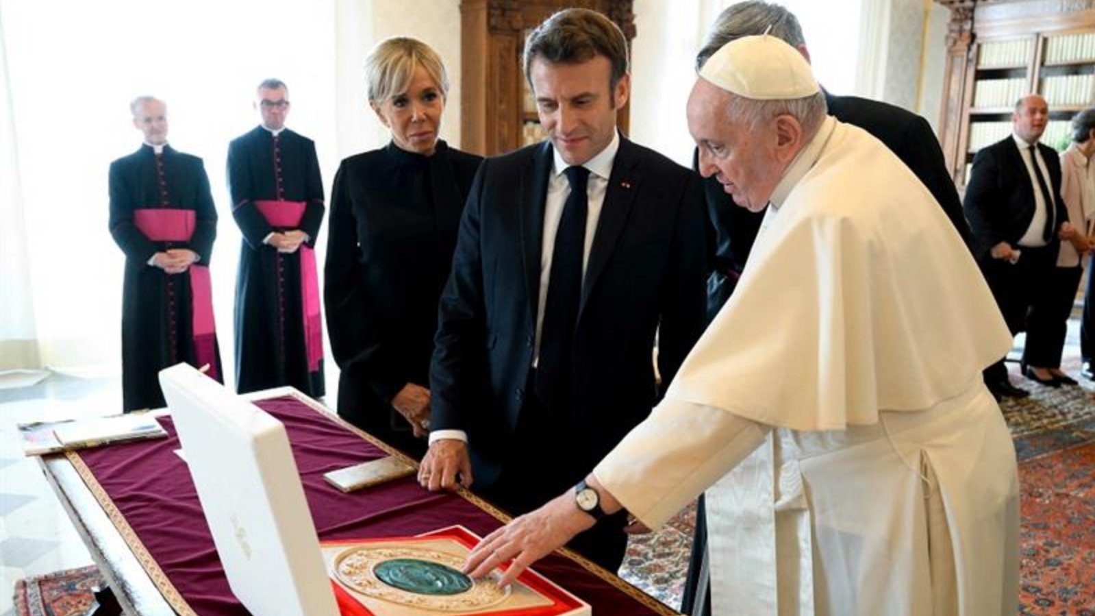 البابا فرانسيس (إلى اليمين) يتبادل الهدايا مع الرئيس الفرنسي إيمانويل ماكرون (وسط) وزوجته بريجيت ماكرون (إلى اليسار) خلال لقاء خاص في الفاتيكان، في 24 أكتوبر 2022