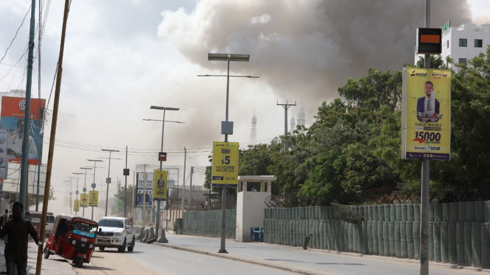 دخان يتصاعد فوق المدينة بينما يسير الناس في أحد الشوارع بعد انفجار كبير بالقرب من وزارة التعليم في مقديشو في 29 أكتوبر 2022