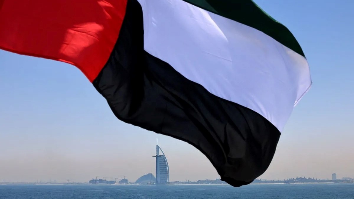 تظهر هذه الصورة التي التقطت في 3 يونيو 2021 علما إماراتيا يرفرف فوق مرسى دبي ويبدو فندق برج العرب في الخلفية