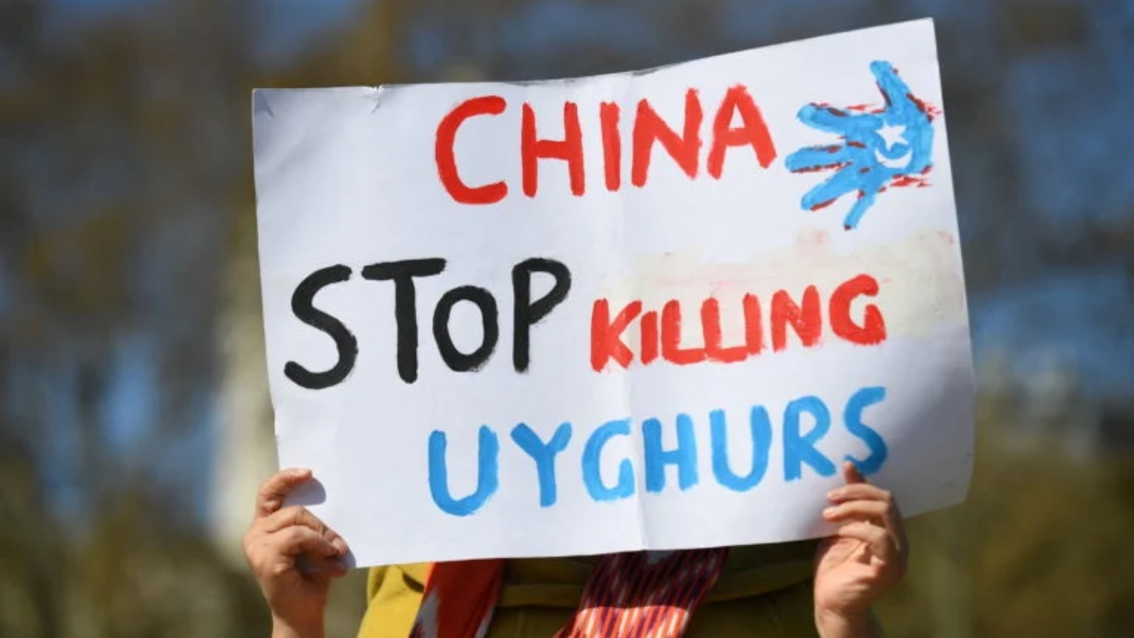 امرأة من مجتمع الأويغور تحمل لافتة أثناء مشاركتها في مظاهرة لدعوة البرلمان البريطاني للتصويت للاعتراف بالاضطهاد المزعوم لأقلية الأويغور المسلمة في الصين باعتباره إبادة جماعية وجرائم ضد الإنسانية في لندن في 22 أبريل 2021