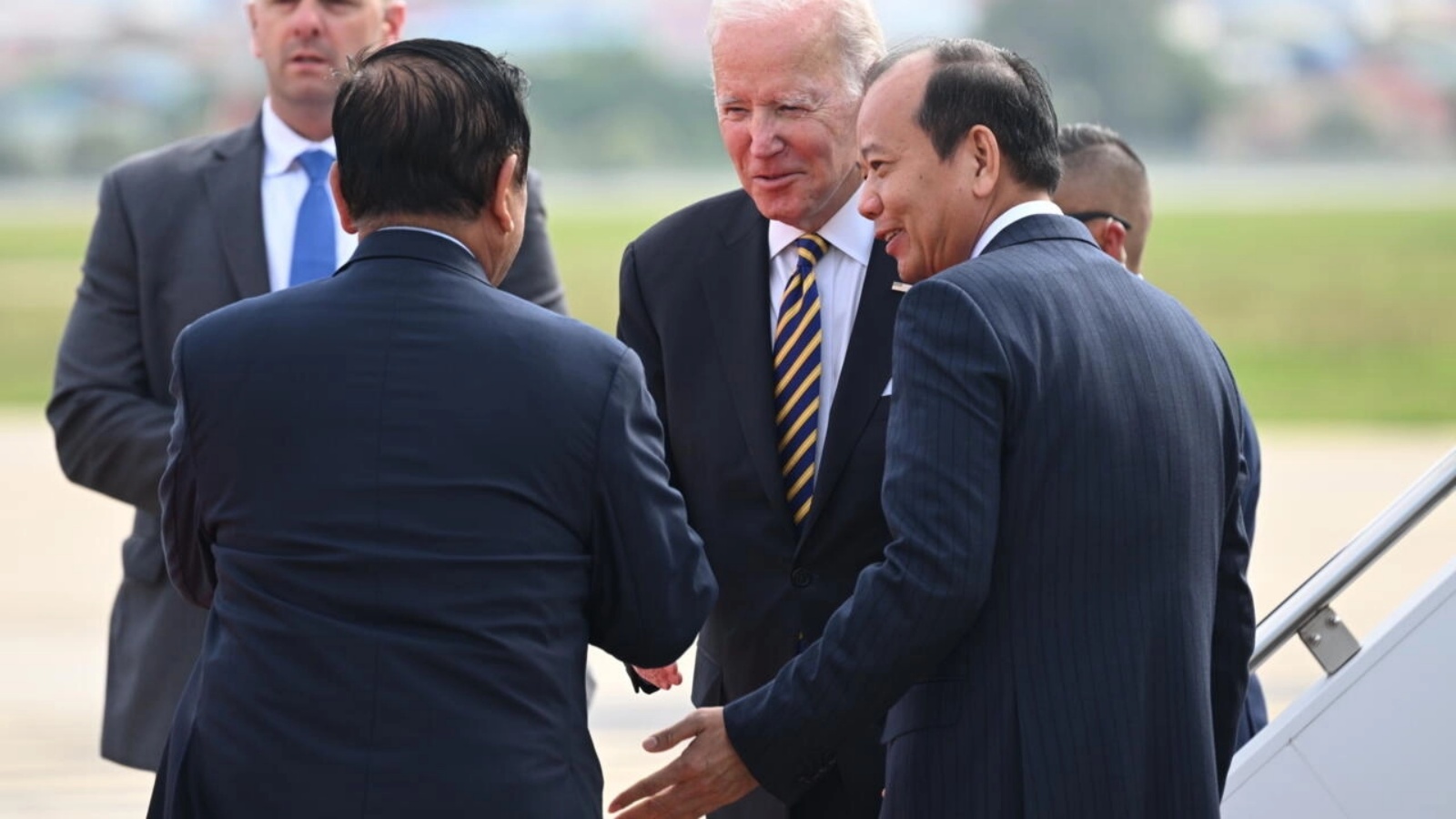 مسؤولون كمبوديون يستقبلون الرئيس الأمريكي جو بايدن (وسط) بعد وصوله إلى بنوم بنه يوم السبت لحضور قمة الآسيان