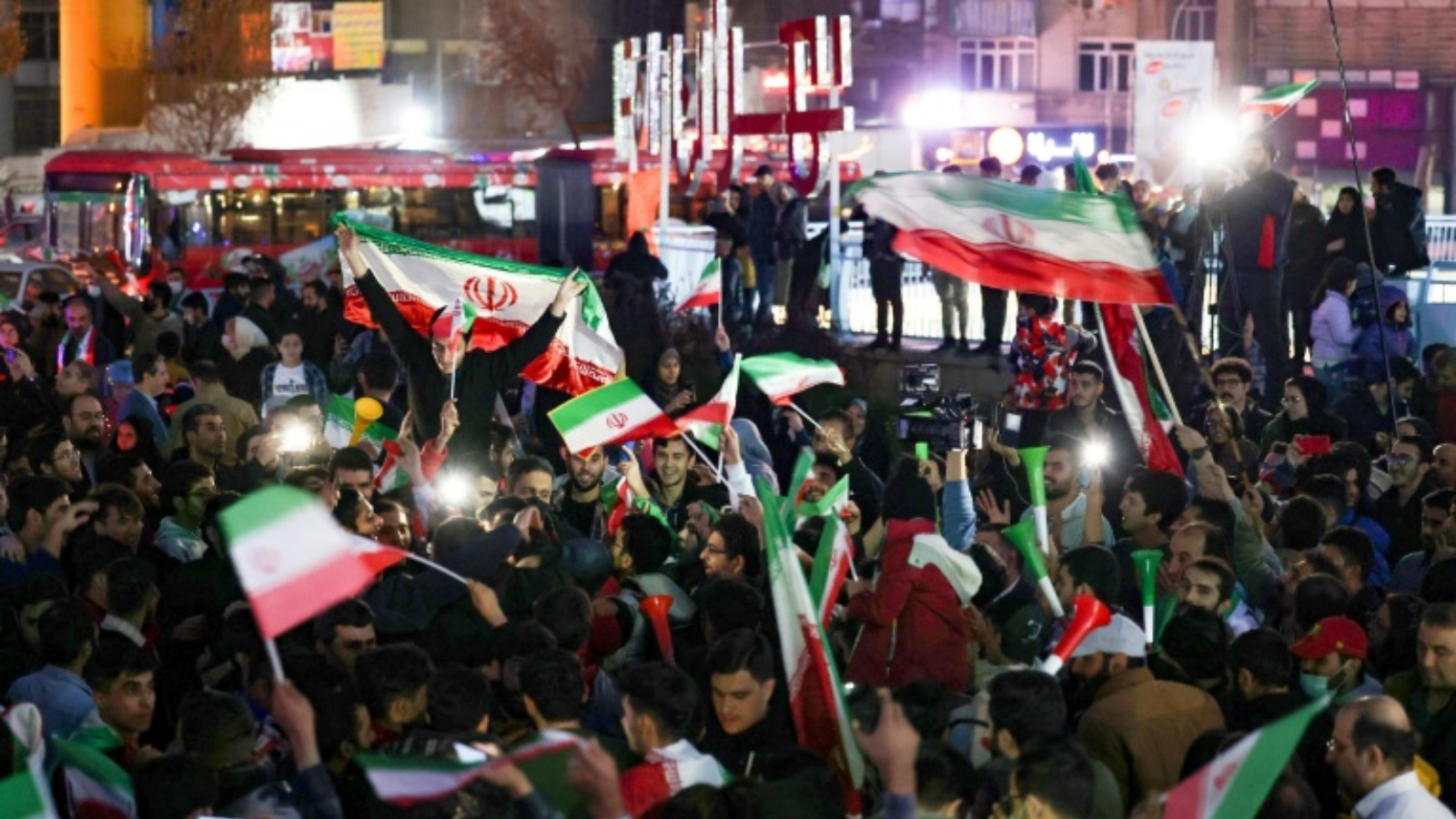 مشجّعون إيرانيون يلوّحون بالأعلام الوطنية أثناء نزولهم إلى شوارع العاصمة طهران للاحتفال بفوز فريقه على ويلز خلال مونديال قطر 2022، في 25 نوفمبر 2022