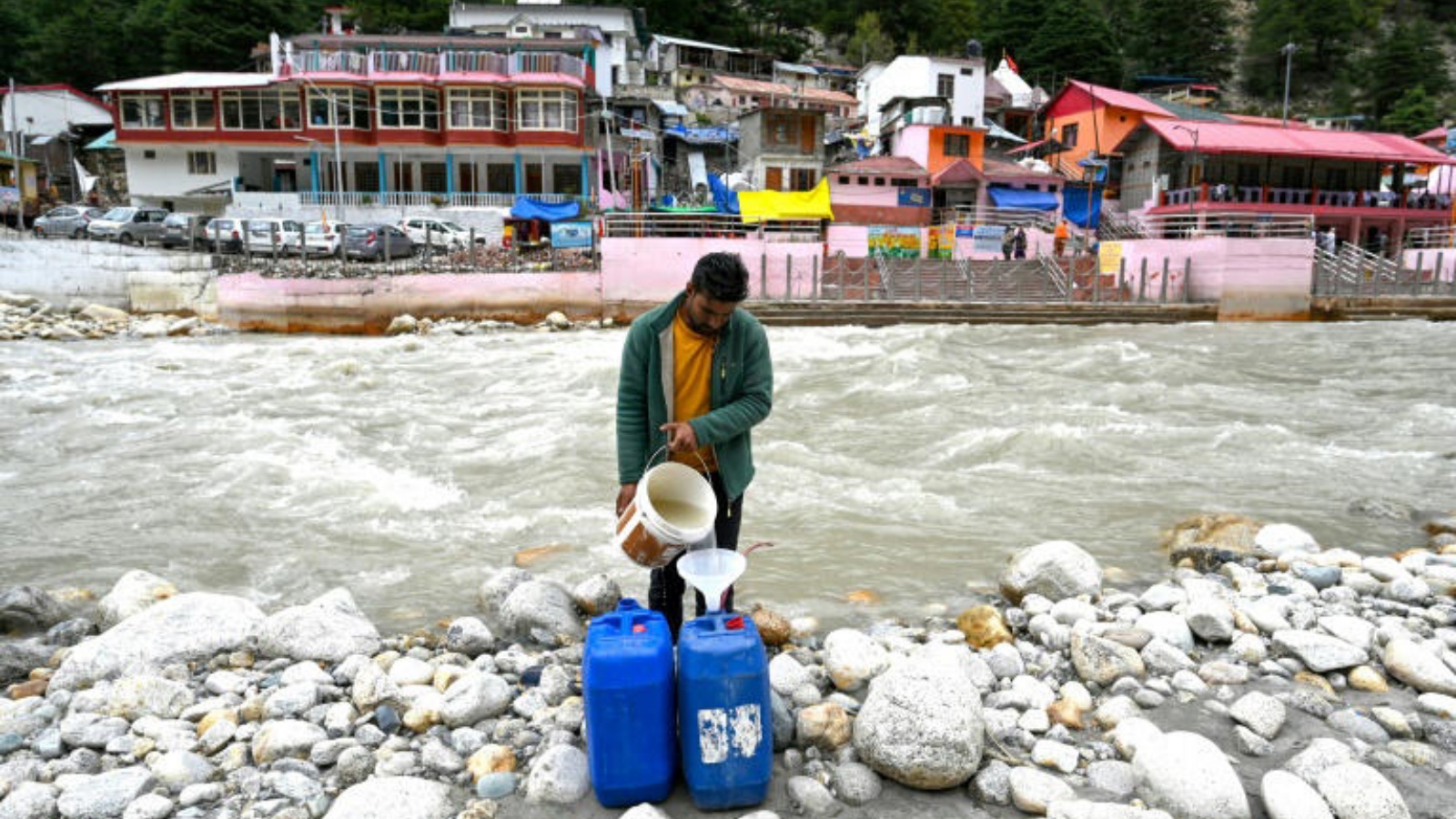 رجل يملأ وعاءً بلاستيكياً بمياه نهر غانغوتري الجليدي، المنبع الرئيسي لنهر الغانج، بتاريخ 15 سبتمبر 2022 في أوتارانتشال الهندية