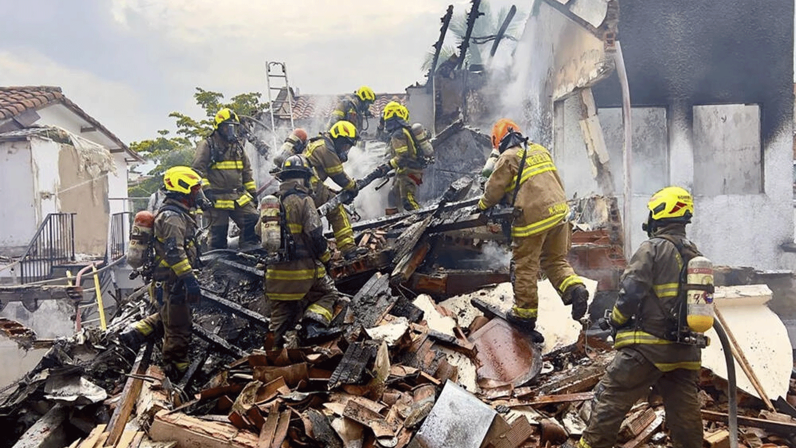 رجال الإطفاء يعملون في حي بيلين روساليس في ميديلين، كولومبيا في الموقع الذي تحطمت فيه طائرة صغيرة وتسببت بمقتل ثمانية أشخاص(مكتب بلدية ميديلين)