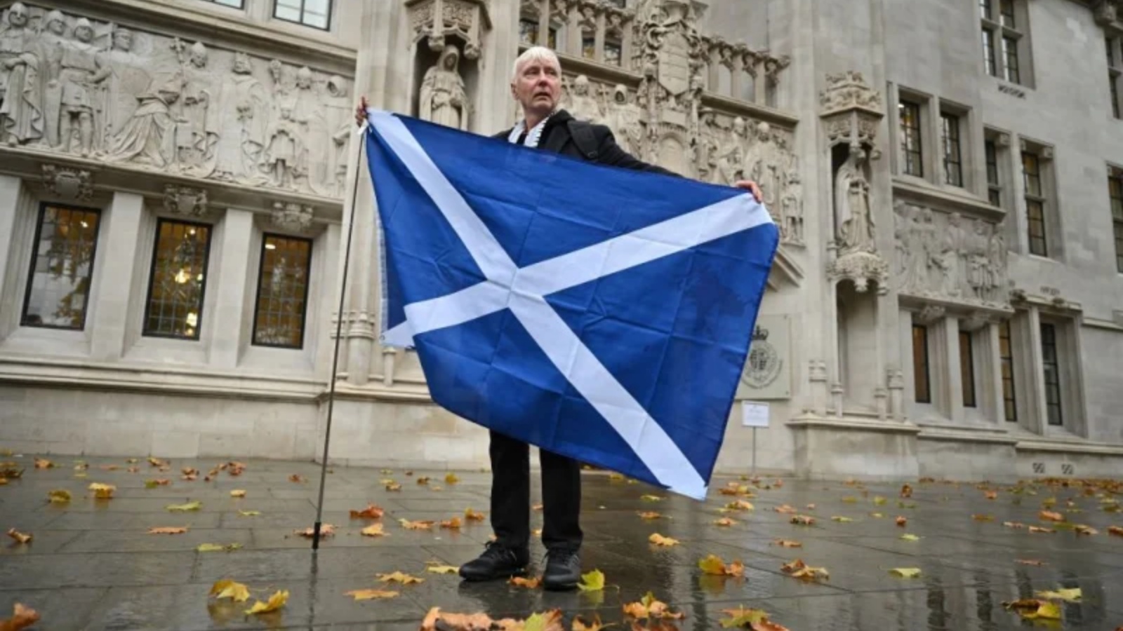 مؤيد استقلال اسكتلندي يقف مع علم اسكتلندا خارج المحكمة العليا في لندن في 23 نوفمبر 2022، بعد أن منعت المحكمة تصويتًا جديدًا على الاستقلال