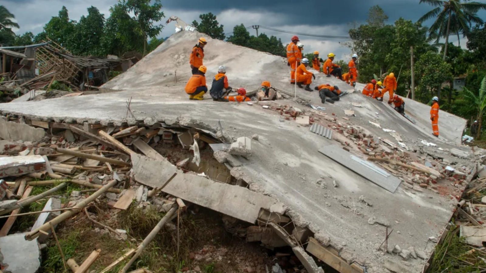 عمال إنقاذ فوق أنقاض أحد الماني المحطمة جراء الزلزال الذي ضرب إندونيسيا