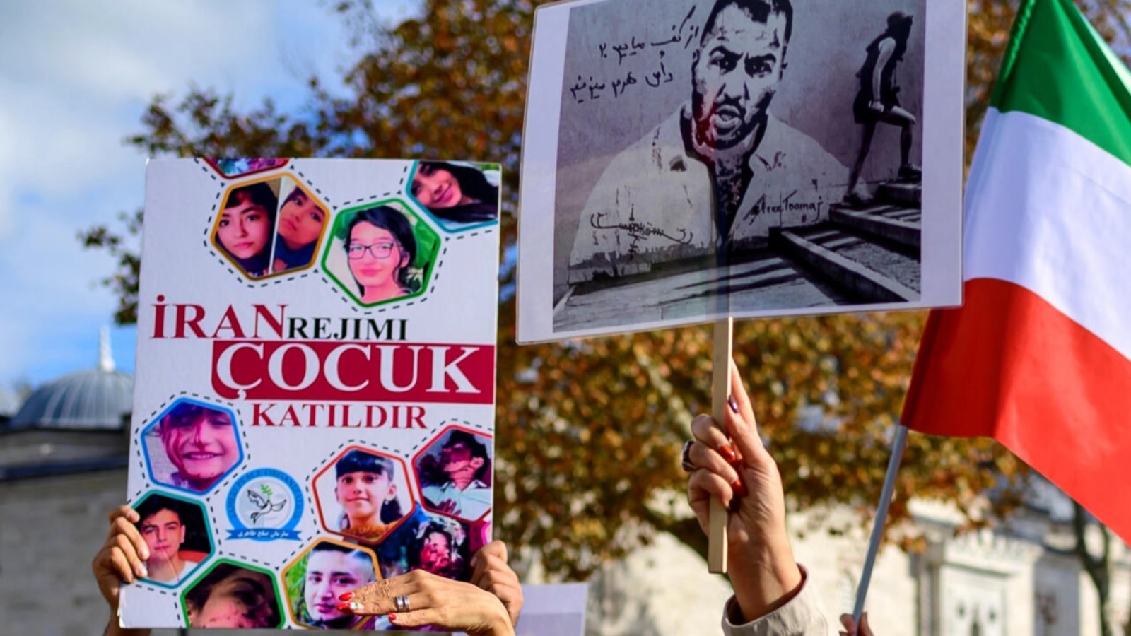 متظاهرون في اسطنبول يرفعون لافتة (يمين) تحمل صورة المغني توماج صالحي بتاريخ 26 نوفمبر 2022