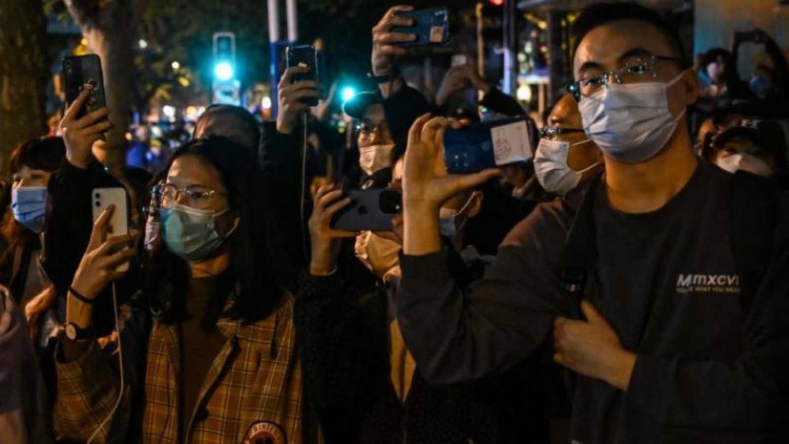 متظاهرون يسيرون في شارع خلال مسيرة لضحايا حريق مميت وكذلك احتجاجاً على قيود الصين القاسية لكورونا في بكين