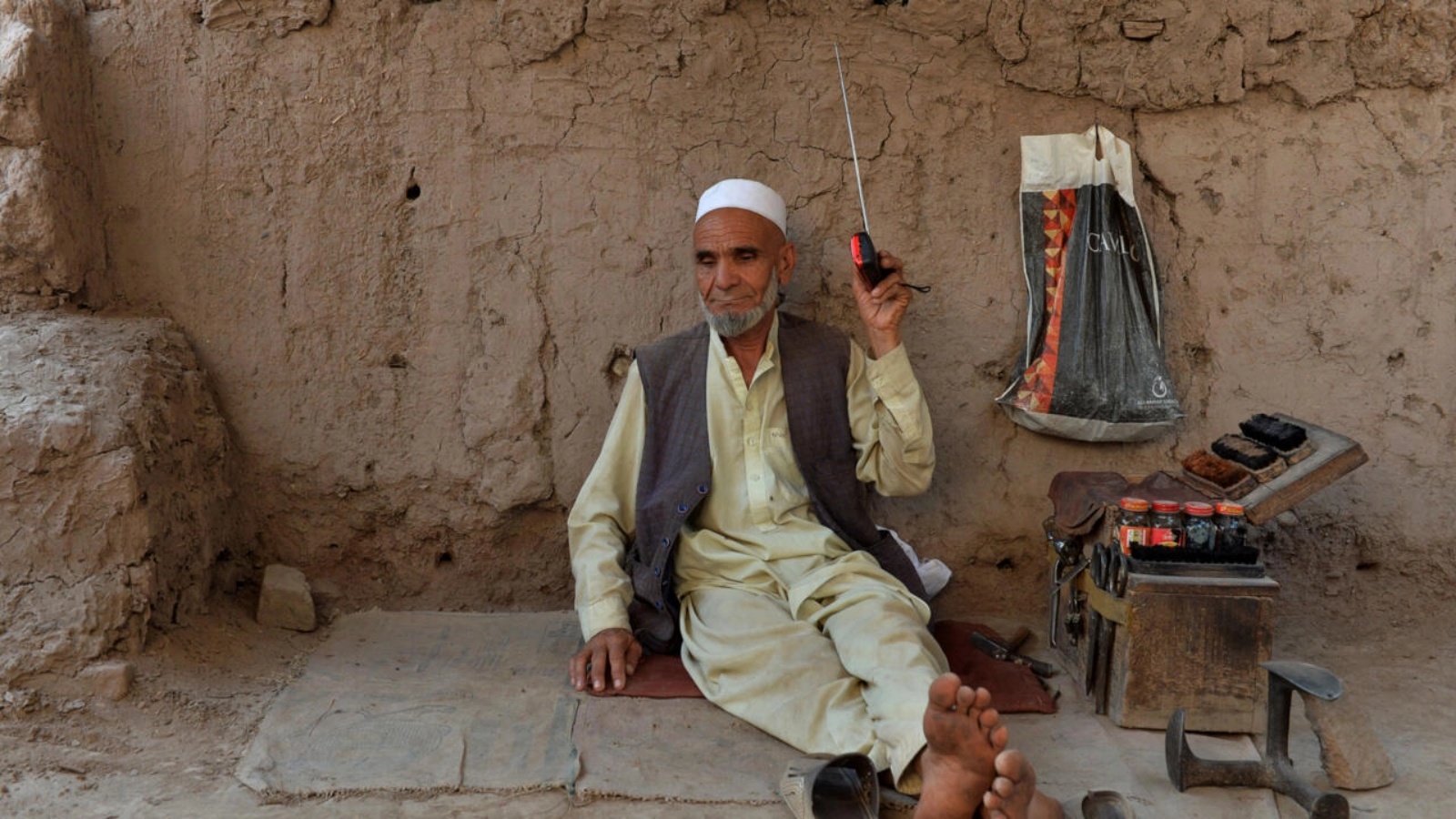 ماسح أحذية يستمع إلى مذياع في 2020 بالقرب من مدينة جلال أباد في أفغانستان