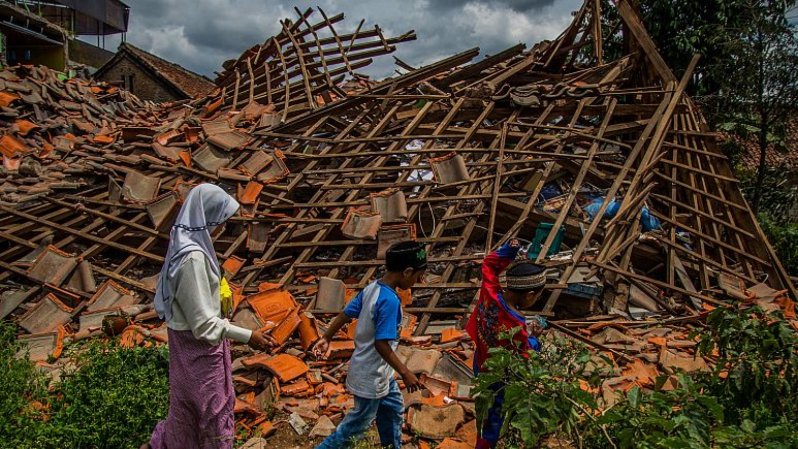 أطفال إندونيسيون يمشون وسط الركام الذي خلفه زلزال ضرب جزيرة جاوا في قرية سوجينانغ في سيانجورز بتاريخ 2 ديسمبر 2022