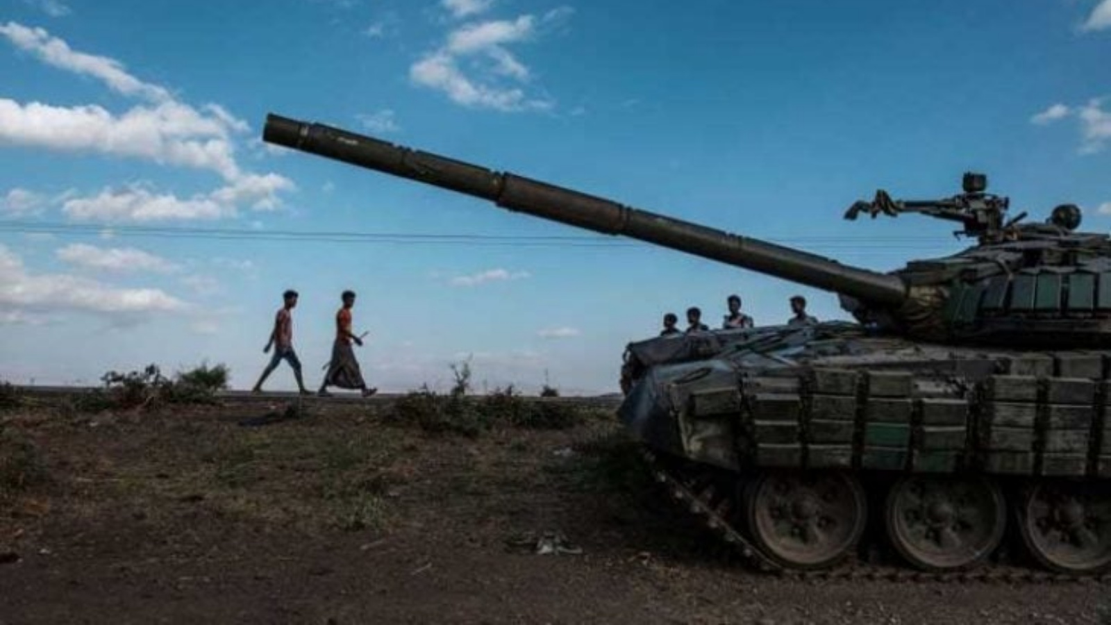 شخصان يعبران أمام دبابة لمتمردي تيغراي في جنوب ميهوني بجنوب الإقليم الواقع في شمال إثيوبيا 