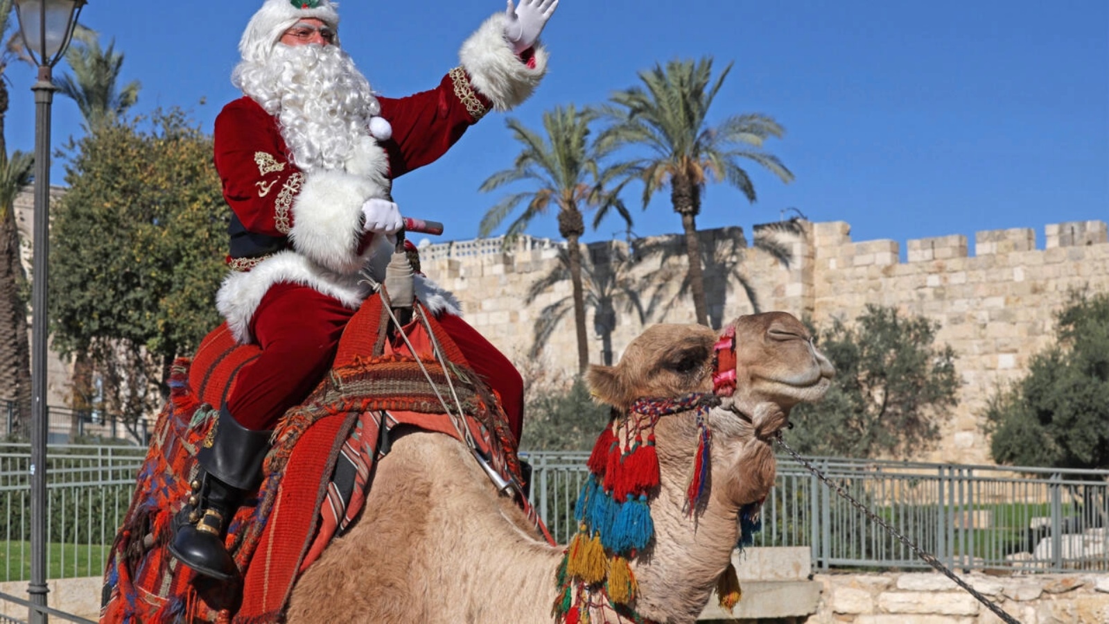 عيسى قسيسية مرتديًا زيّ بابا نويل أثناء ركوبه جملًا في البلدة القديمة في القدس الشرقية في الثاني من ديسمبر 2022 