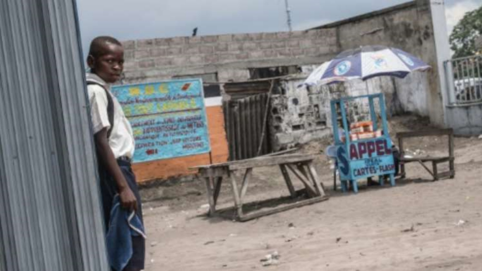طفل يقف بجوار كشك على الطريق يبيع بطاقات الهاتف الخلوي والانترنت في كينشاسا في عام 2015