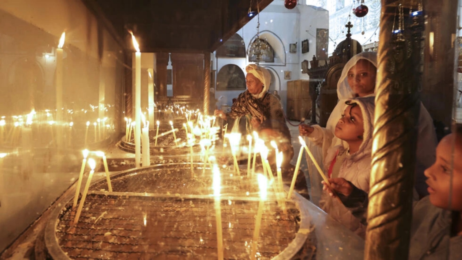 مصلون وسياح يضيئون الشموع داخل كنيسة المهد في مدينة بيت لحم في الضفة الغربية في 22 ديسمبر 2022 