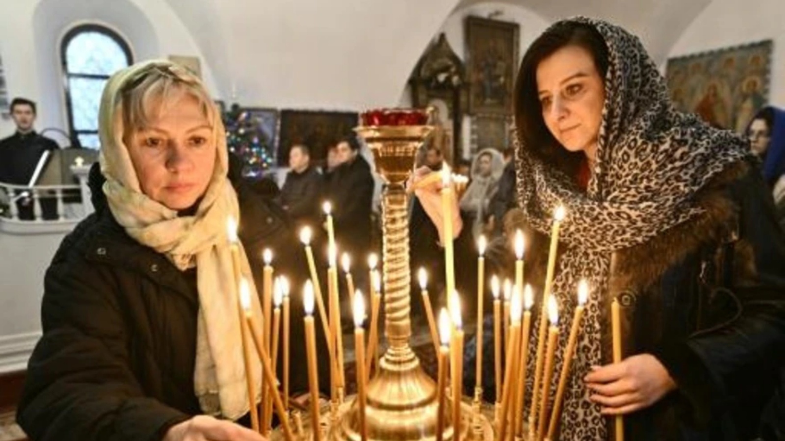 تضيئان الشموع في كنيسة أرثوذكسية في كييف خلال مراسم الاحتفال بعيد الميلاد في 25 ديسمبر 2022
