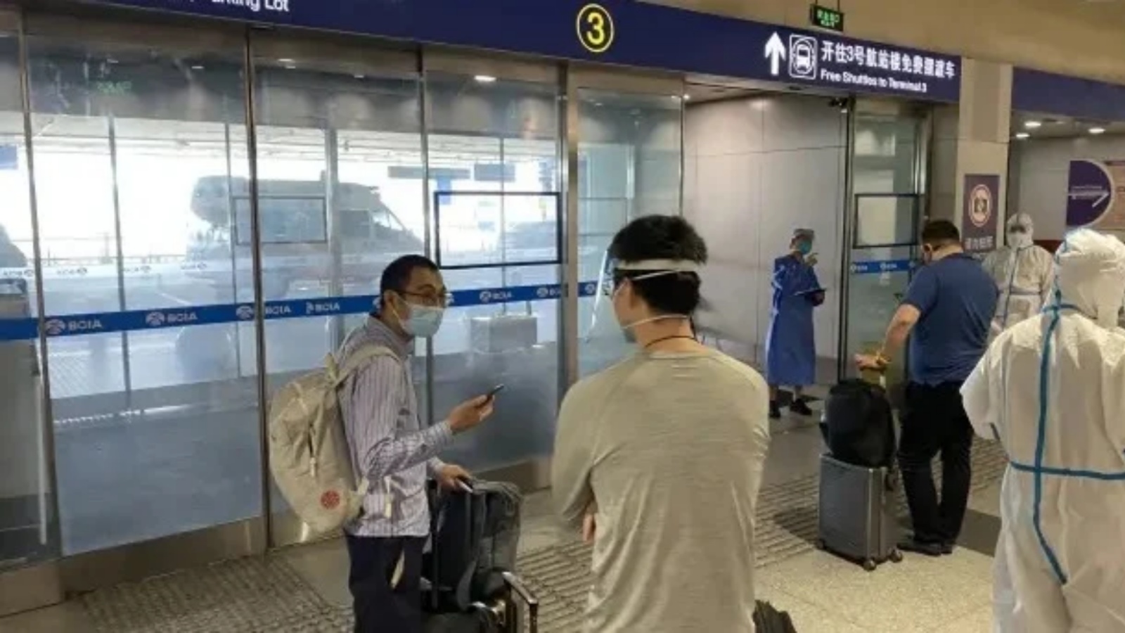 مسافرون ينتظرون نقلهم إلى الوجهات المعينة للحجر الصحي في مطار بكين الدولي في 18 يونيو 2022