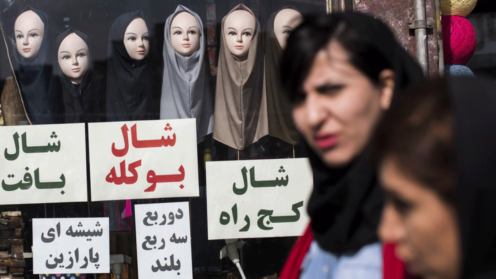 نساء في طهران يمشون أمام متجر لبيع الحجاب