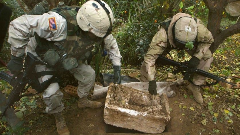 جنديان أميركيان يزيلان الحجر الذي كان يسد الحفرة التي وجد فيها الرئيس العراقي الراحل صدام حسين
