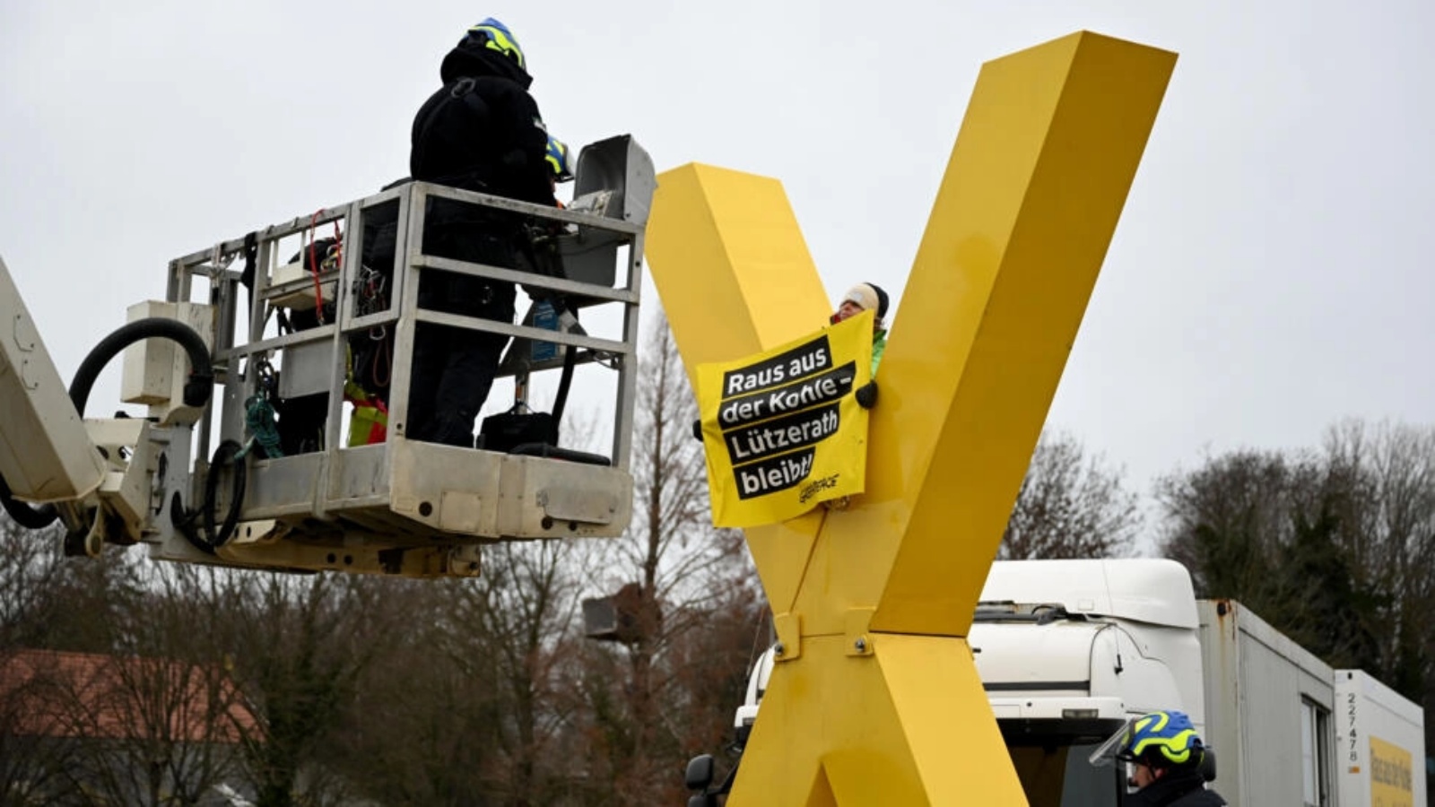 يستعد رجال الشرطة على منصة رفع لإزالة ناشط مناهض للفحم يجلس على تمثال X أصفر عملاق في 10 يناير 2023 في Luetzerath ، غرب ألمانيا
