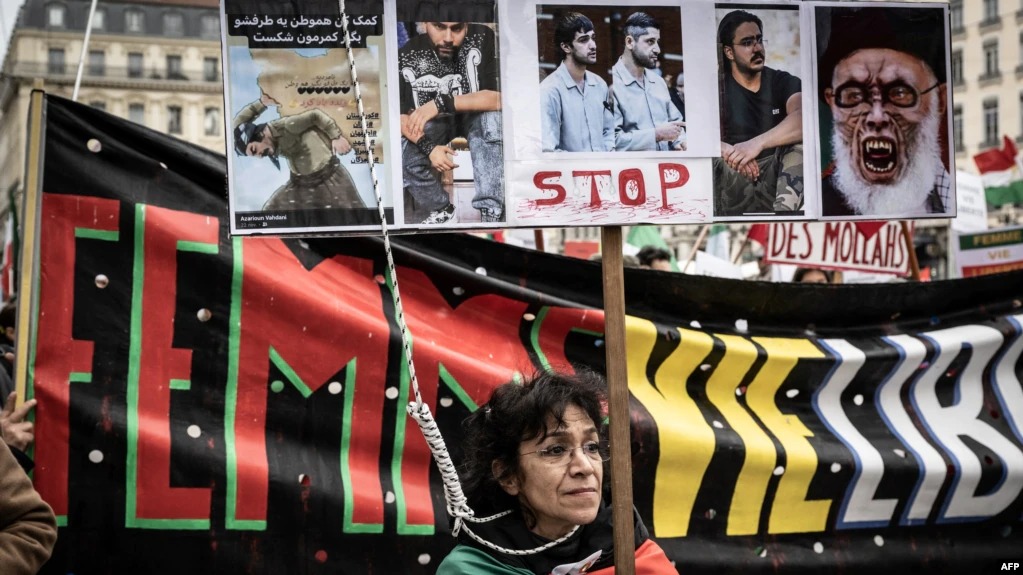 متظاهرة تحمل صورًا لمتظاهرين تم إعدامهم في إيران خلال مسيرة في ليون، فرنسا، في 8 يناير 2023
