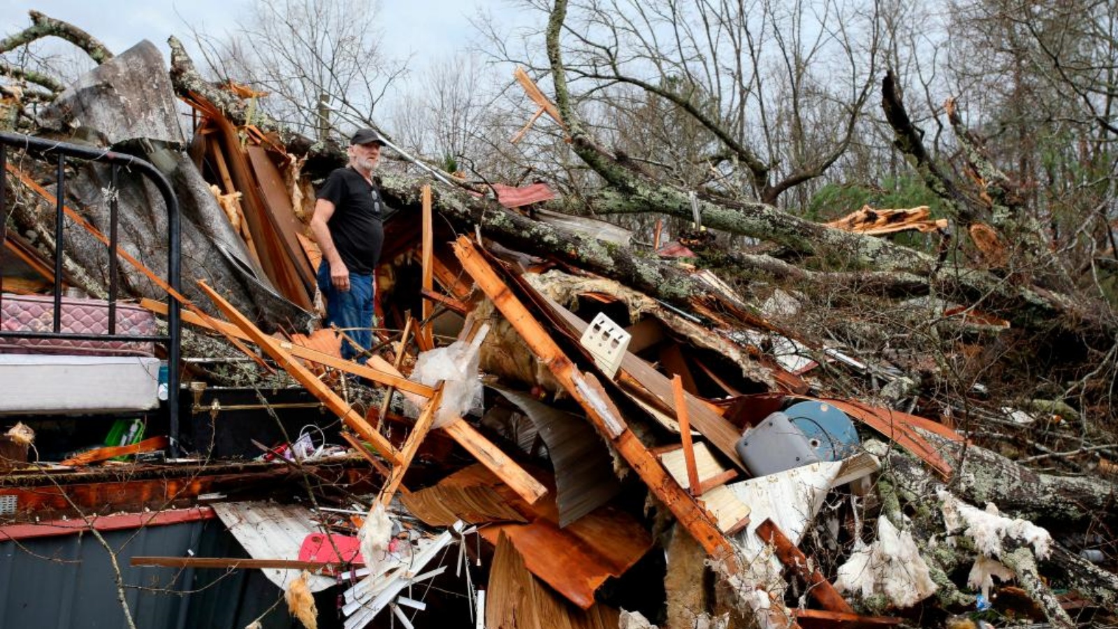 رجل يقف بين أنقاض منزله المتنقل، الذي دُمر بعدما سقطت عليه شجرة بالقرب من أكرون في مقاطعة هيل، ألاباما، الولايات المتحدة ، 12 يناير 2023