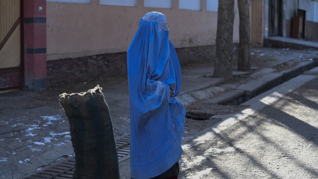 امرأة بالبرقع تقف بجانب كيس من الفحم تبرع به فريق تطوعي في كابول، في 13 يناير 2023