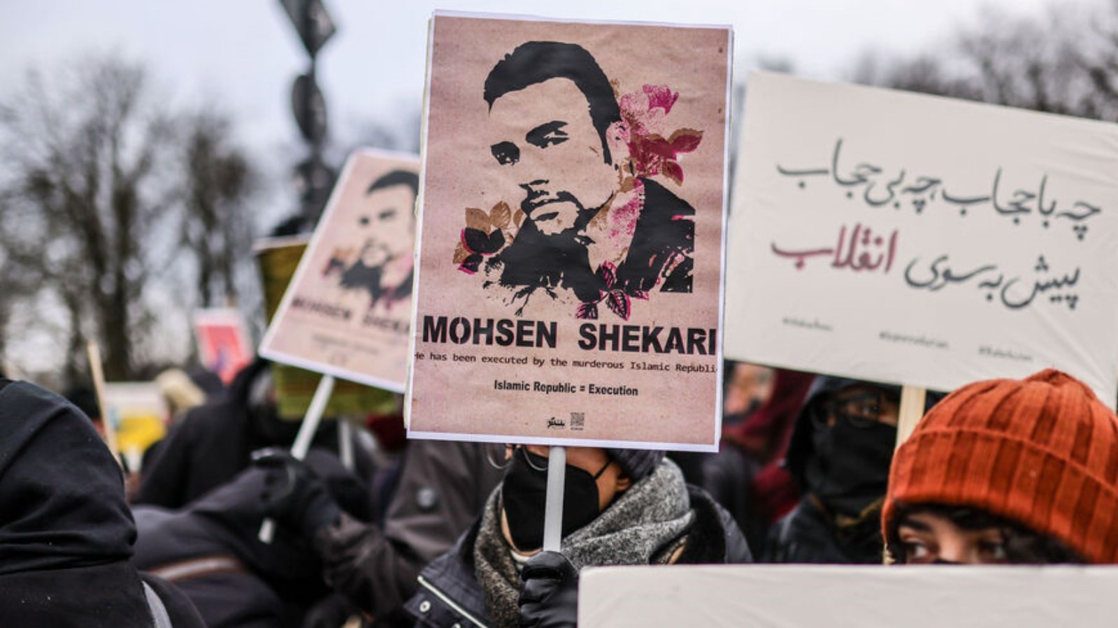 أحد المشاركين يرفع لافتة تحمل صورة المتظاهر الإيراني محسن شكاري الذي تم إعدامه مؤخرًا، أثناء احتجاج تضامنًا مع المظاهرات المستمرة في إيران وضد نظام الجمهورية الإسلامية، أمام بوابة براندنبورغ في 10 ديسمبر 2022، في برلين، ألمانيا