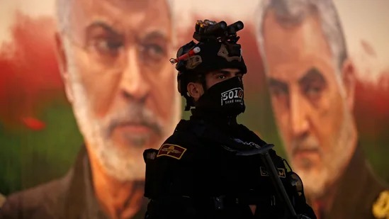 أحد عناصر الحرس الثوري الإيراني أمام صورة لقاسم سليماني في طهران