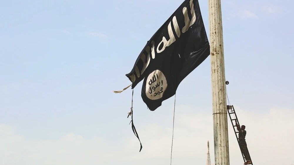 عضو في قوات سوريا الديمقراطية المدعومة من الولايات المتحدة ينزل علم الدولة الإسلامية الممزق في الطبقة، سوريا، في أبريل 2017