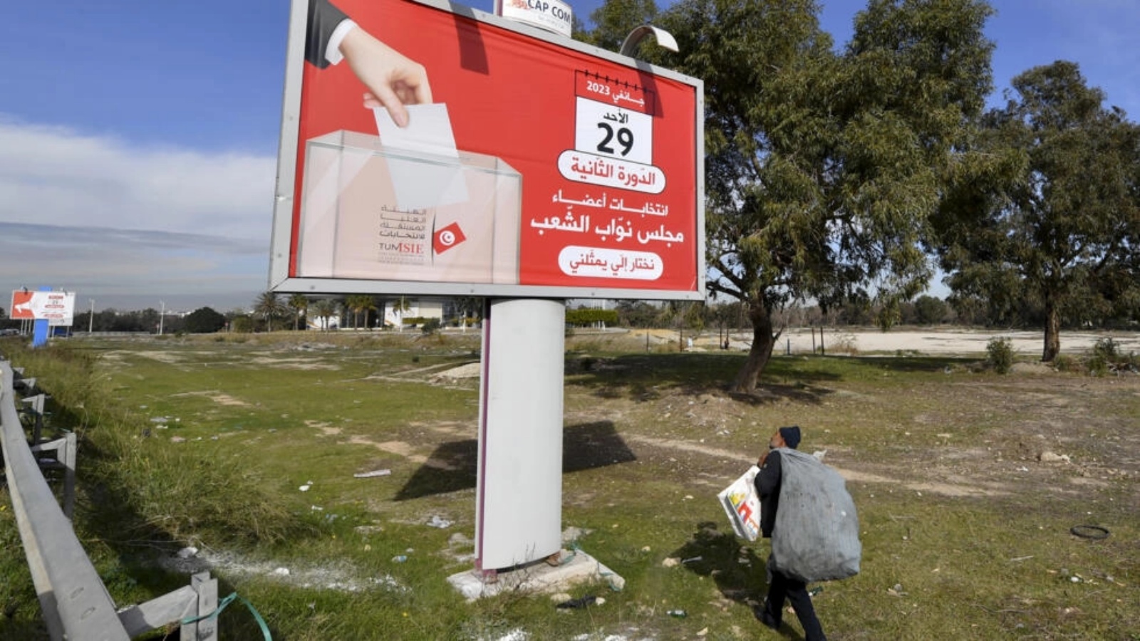 عامل يمر قرب لافتة للحملة الانتخابية النيابية في تونس في 25 يناير 2023