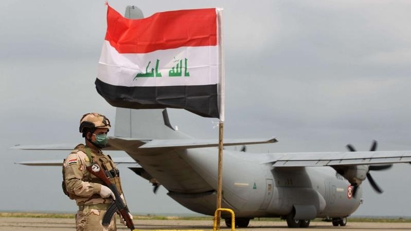 جندي عراقي يقف في حراسة أمام حاملة الطائرات العسكرية الأميركية في قاعدة القيارة الجوية بالعراق