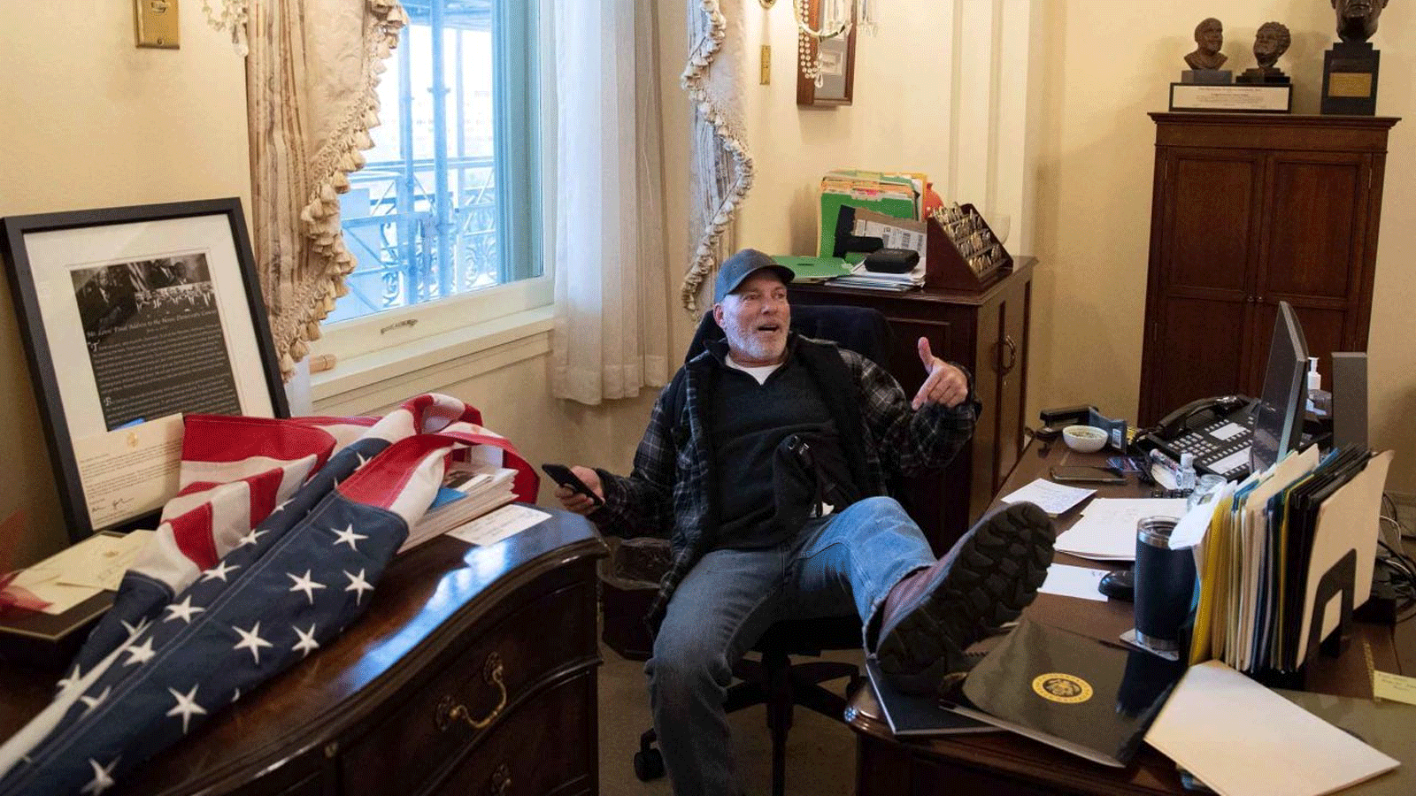 ريتشارد بارنيت، من أنصار الرئيس الأميركي دونالد ترامب، يجلس داخل مكتب رئيسة مجلس النواب الأميركي نانسي بيلوسي أثناء احتجاجه داخل مبنى الكابيتول الأميركي في واشنطن العاصمة. 6 كانون الثاني\يناير 2021